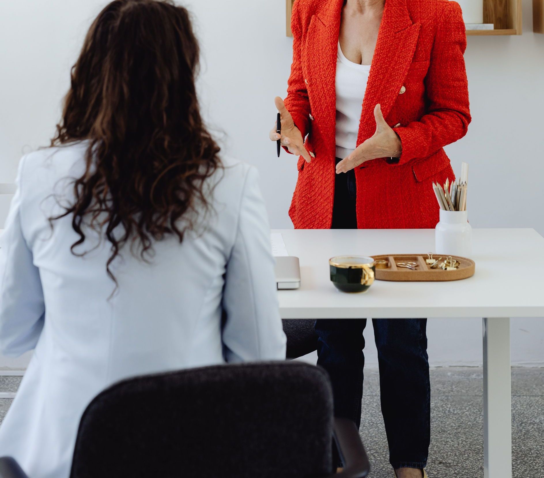 Senior woman in red blazer presenting during a business meeting in a modern office.