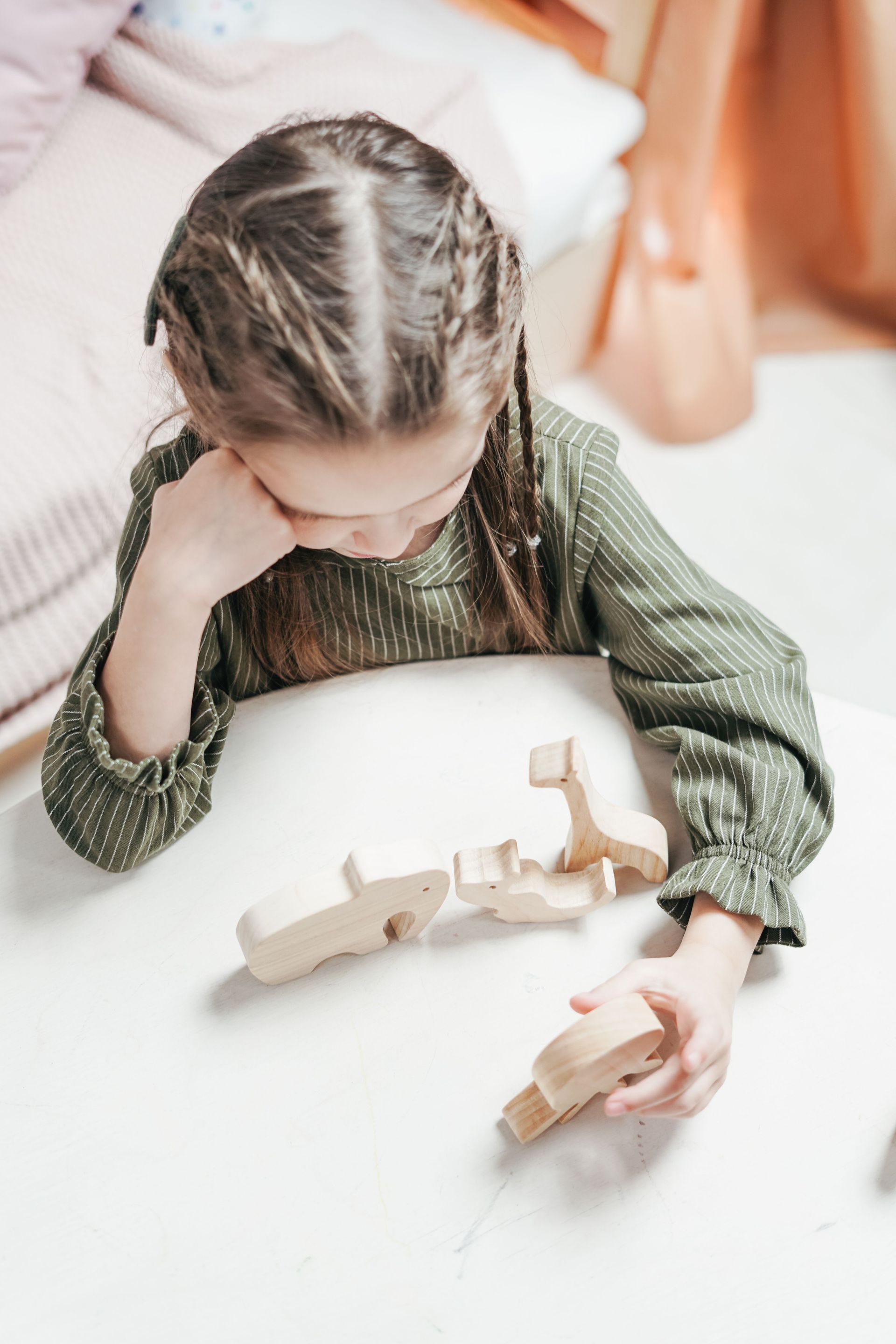 Young girl plays with wooden toys, fostering creativity and learning, in a cozy indoor setting.